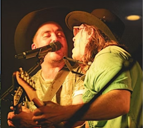 2 men singing holding a guitar